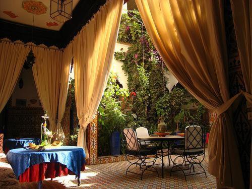 a patio with curtains and a table and chairs at Riad Maryam Taroudant in Taroudant