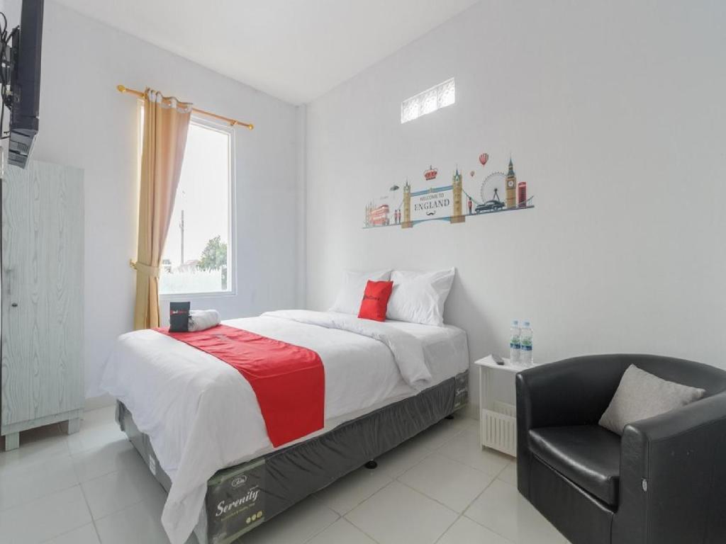 ein weißes Schlafzimmer mit einem Bett und einem Stuhl in der Unterkunft RedDoorz Plus near Taman Rasuna Menteng in Jakarta