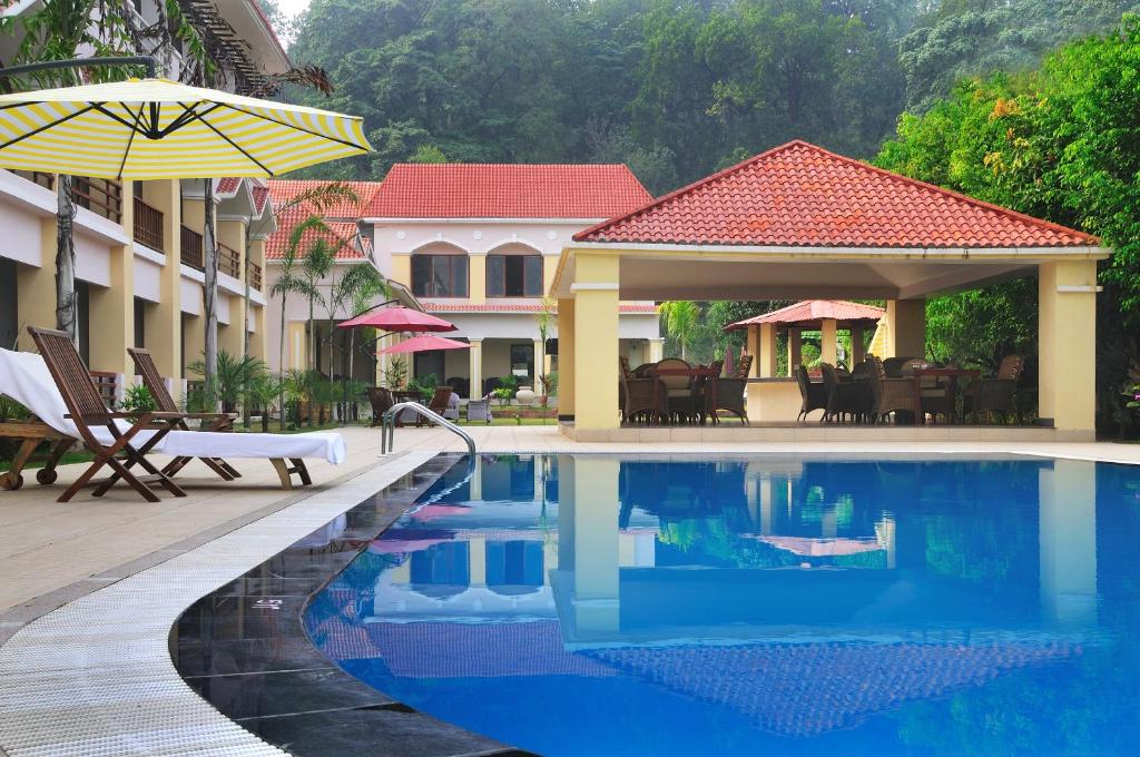 a swimming pool in front of a house with an umbrella at Le Roi Corbett in Garjia