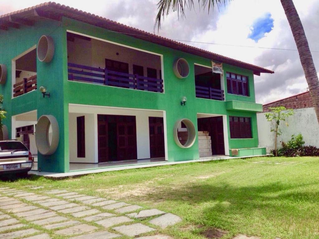 une maison verte avec une voiture garée devant elle dans l'établissement Casa Verde Albuquerque, à Fortaleza