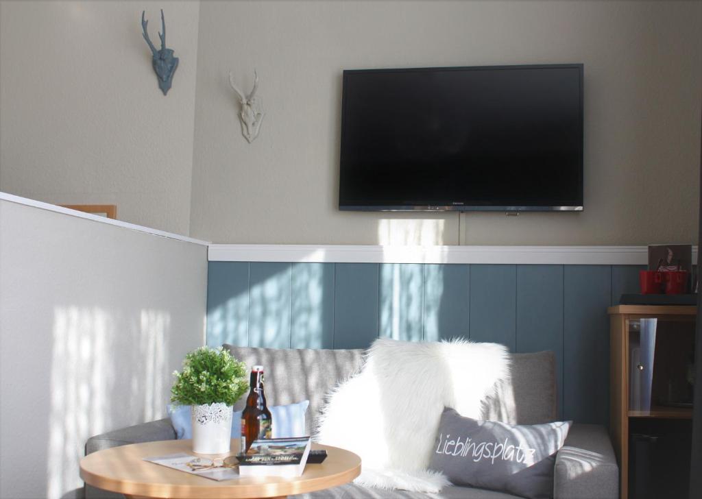 ein Wohnzimmer mit einem Sofa mit einem Tisch und einem Flachbild-TV in der Unterkunft Hotel am Kurpark in Bad Lauterberg