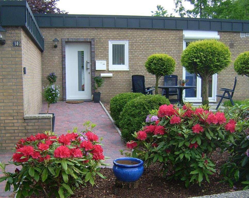 ein Haus mit roten Blumen und einem blauen Topf in der Unterkunft Ferienhaus "Pusteblume" in Bad Zwischenahn