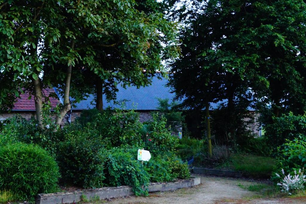 einen Garten mit Büschen und Bäumen vor einem Gebäude in der Unterkunft Aux Greniers à Rêves in Plestan
