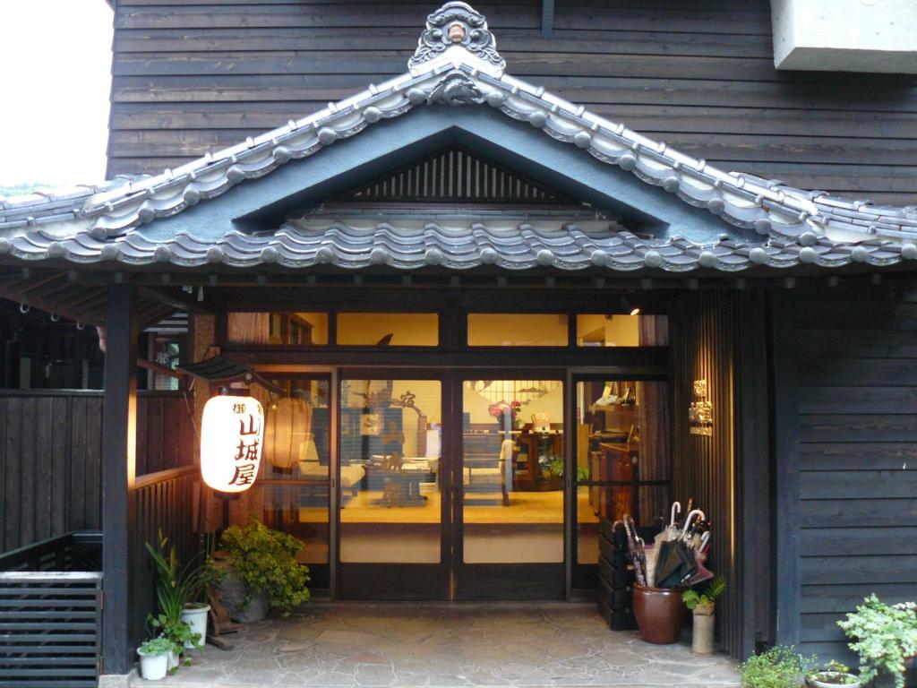 Przednia część sklepu z chińskim dachem na górze w obiekcie Ryokan Yamashiroya w mieście Yufu