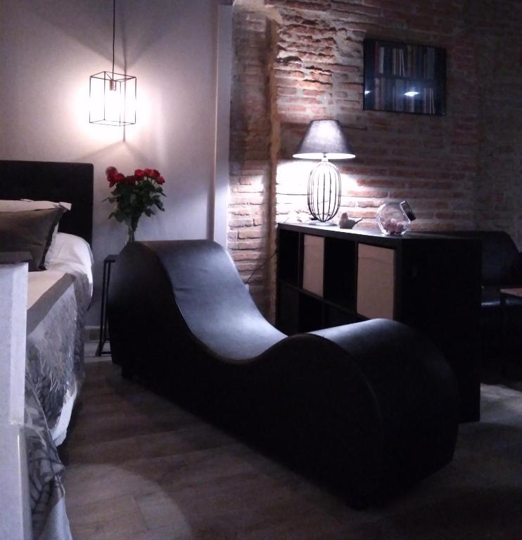 a bedroom with a bed and a table with a lamp at La Suite Romantique avec Jacuzzi au Cœur de Perpignan in Perpignan