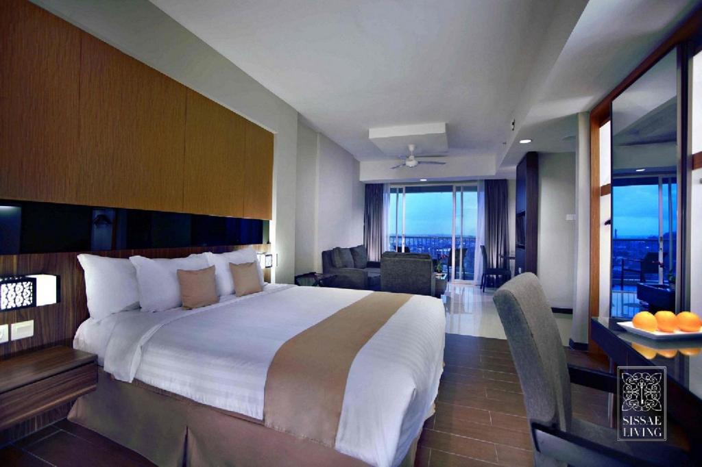 a bedroom with a large bed and a living room at The Malibu Suites Balikpapan by Sissae Living in Balikpapan