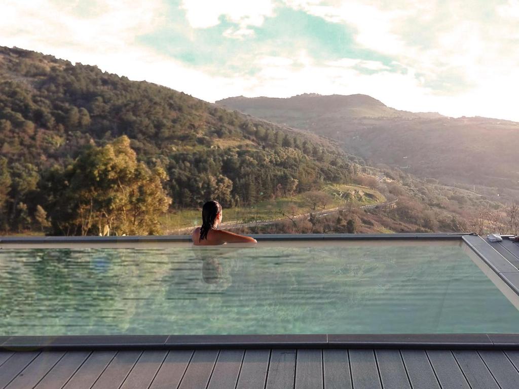 a woman is standing in a swimming pool overlooking a mountain at Tuffudesu Experience in Osilo