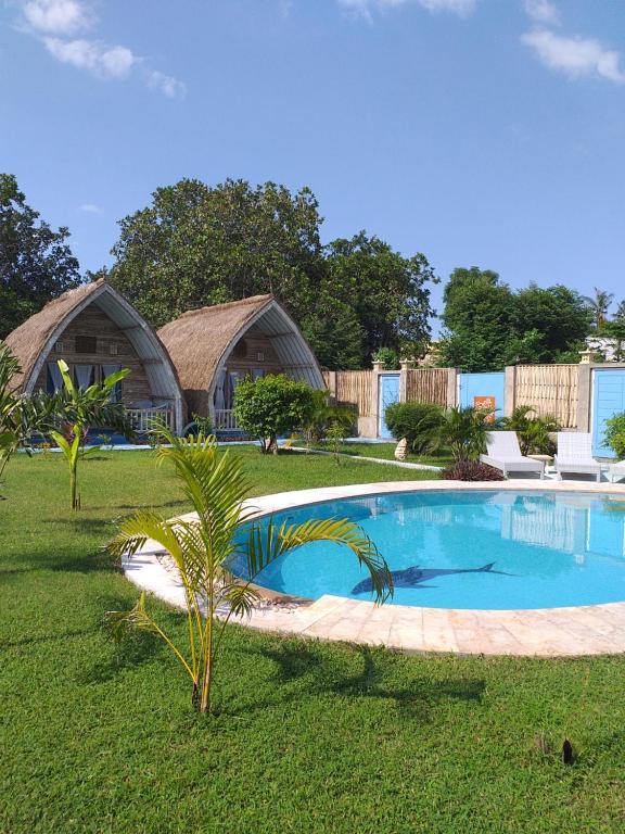 a swimming pool in a yard with two huts at Casa Azzurra in Gili Islands