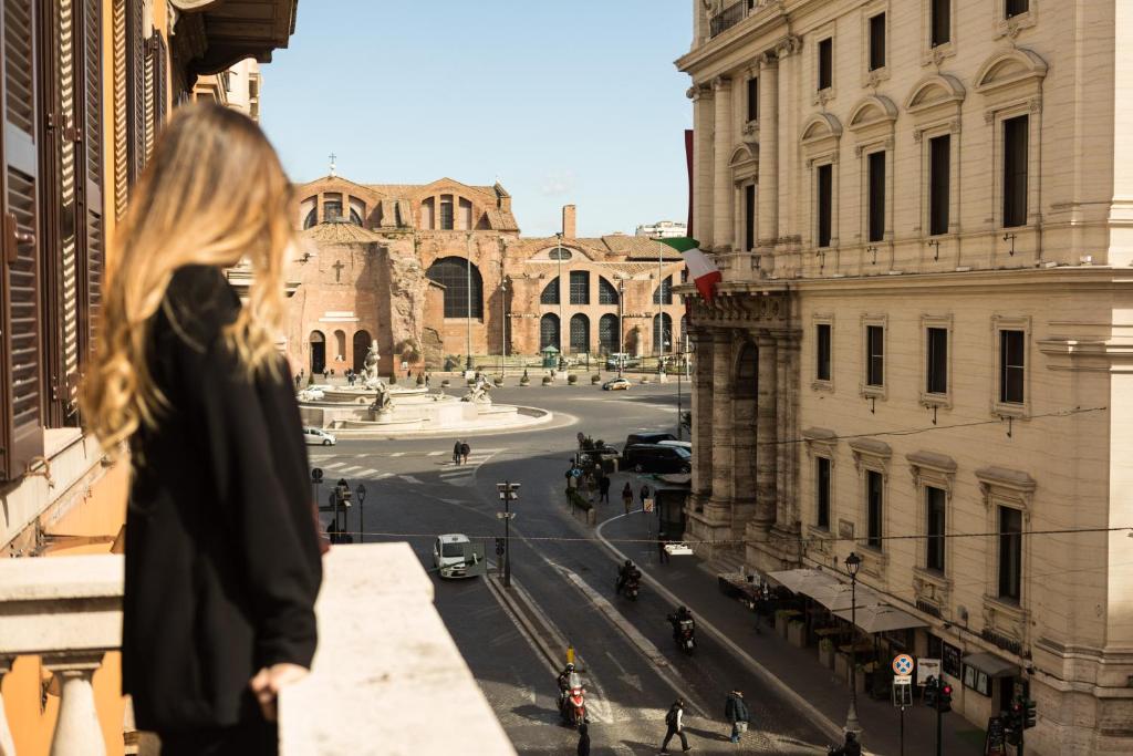 Una donna in piedi su un cornicione che guarda una strada di città di Bespoke Roma Suites a Roma