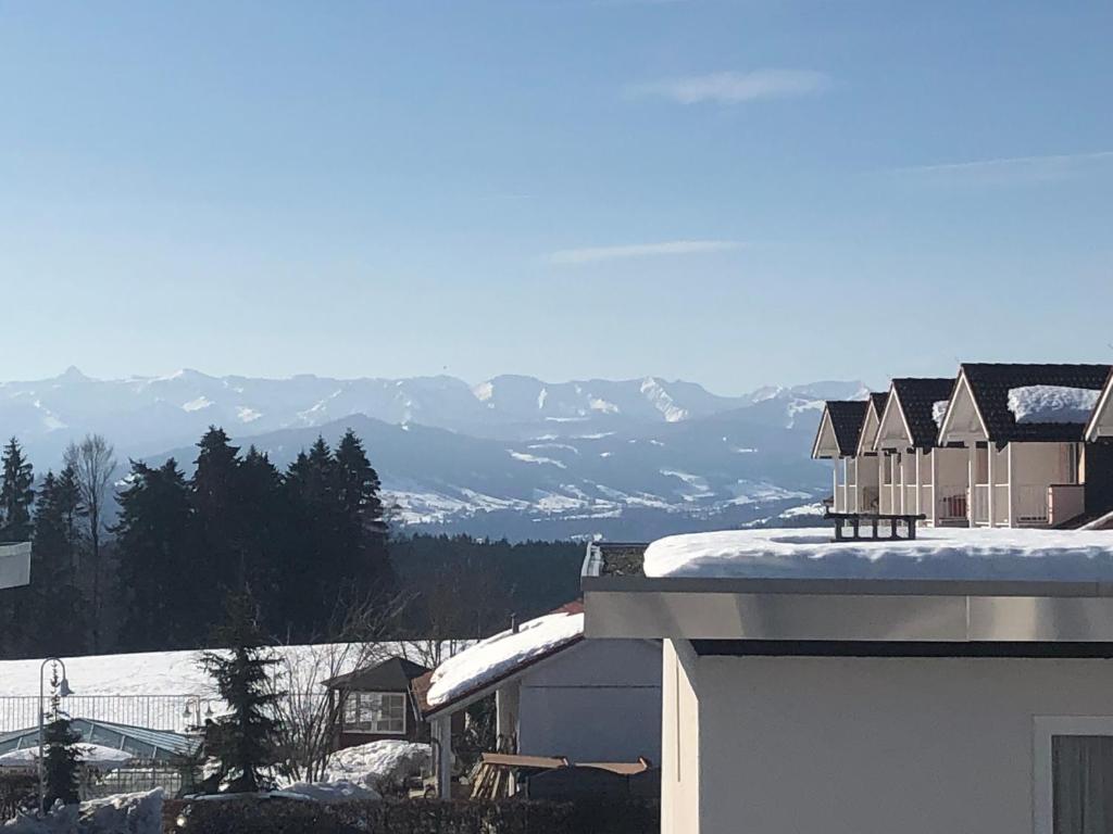 un techo cubierto de nieve de una casa con montañas en el fondo en Appartement Allgäu-Sonne en Scheidegg