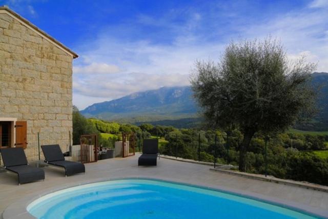 una piscina con due sedie e un edificio di Maison de campagne, deux chambres, vue sur les montagnes a Sartène