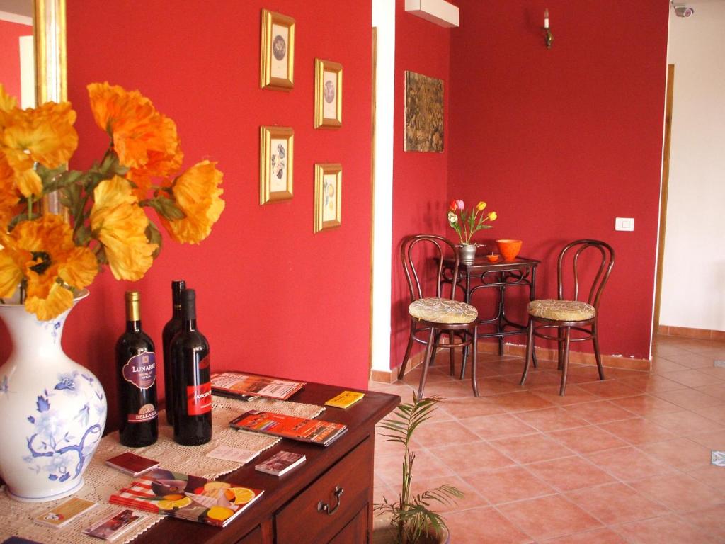 Pokój z czerwoną ścianą ze stołem i butelkami wina w obiekcie B&B Villa Maria Giovanna w mieście Giardini Naxos