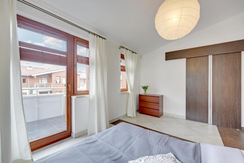 a bedroom with a bed and a large window at Grand Apartments - Neptun Park. in Gdańsk