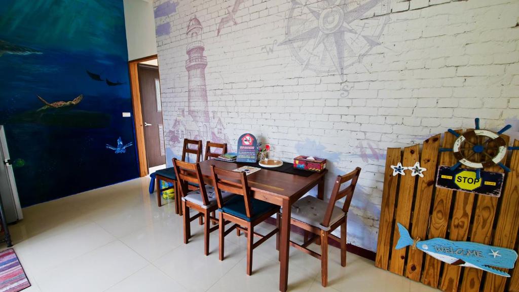 a dining room with a table and chairs and a wall at Sabai B&amp;B 澎湖船家寶民宿 in Huxi