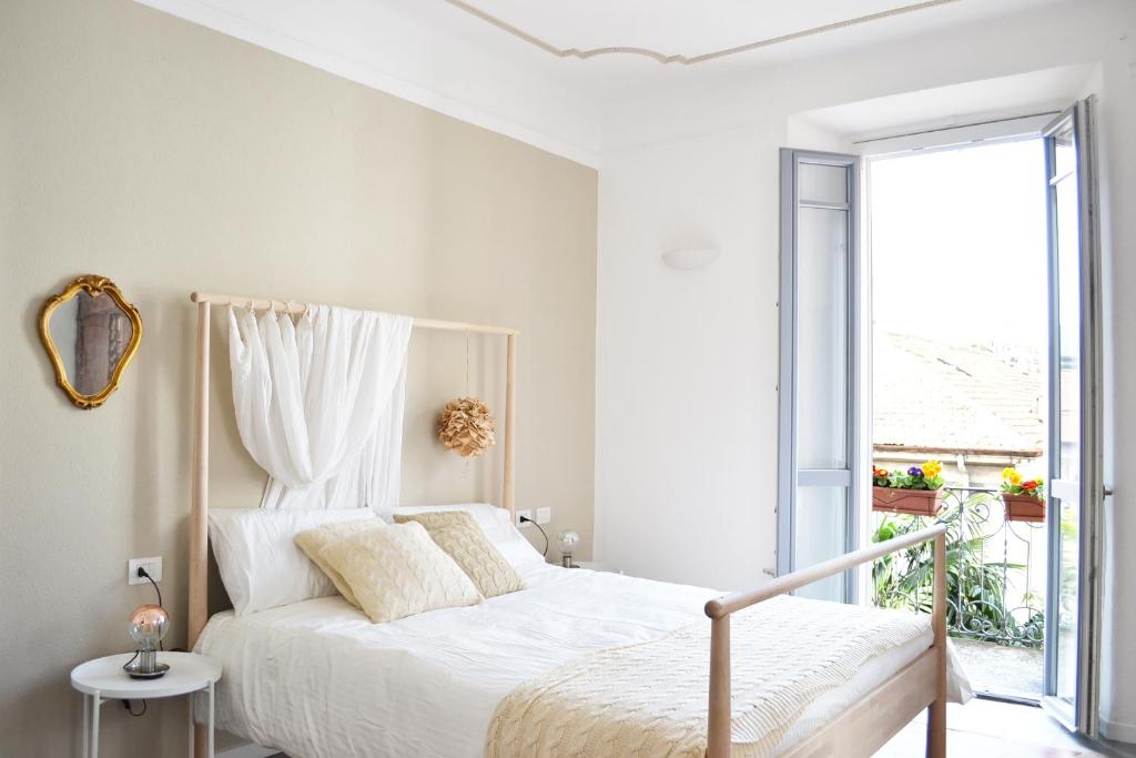een witte slaapkamer met een bed en een raam bij Italian Fairytale Apartment by Rent All Como in Como