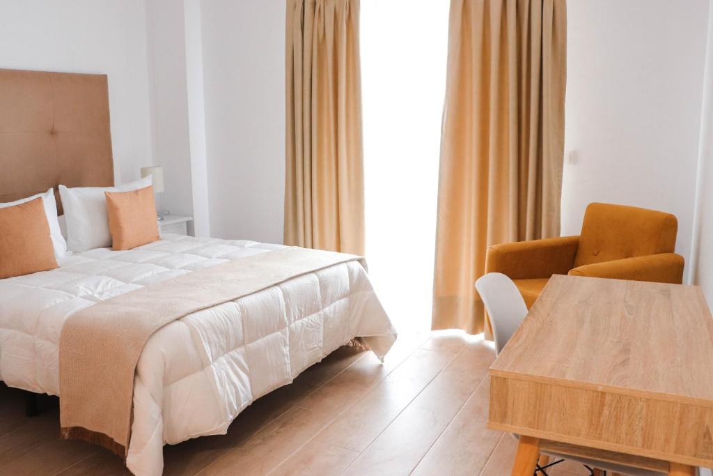 a bedroom with a bed and a chair and a table at Hostal Castillo in San José de la Rinconada