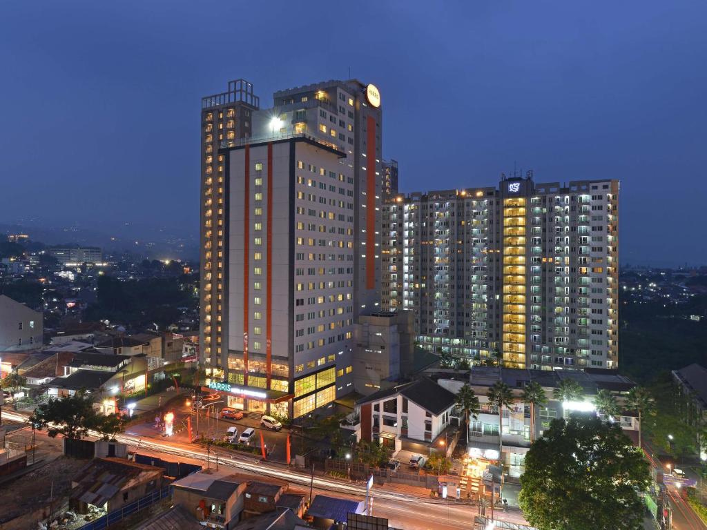 un edificio alto con luces encendidas en una ciudad por la noche en HARRIS Hotel & Conventions Ciumbuleuit - Bandung, en Bandung