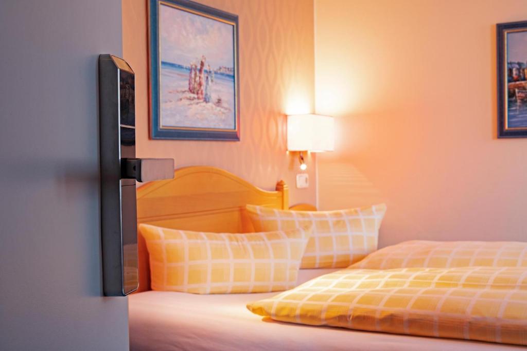 ヴァーネミュンデにあるDünenhotel am Meerのベッドルーム1室(黄色と白の枕が備わるベッド2台付)