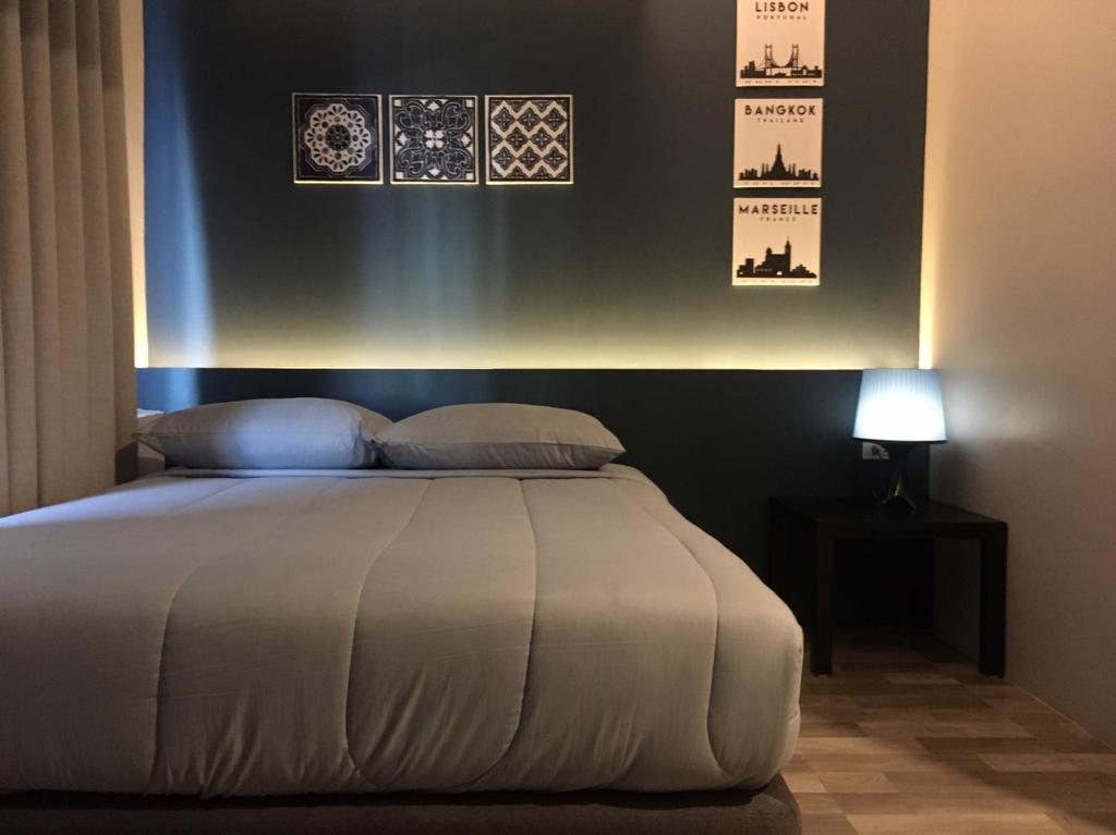 A dark-accented bedroom has a large bed, bedside table, and illuminated wall display.