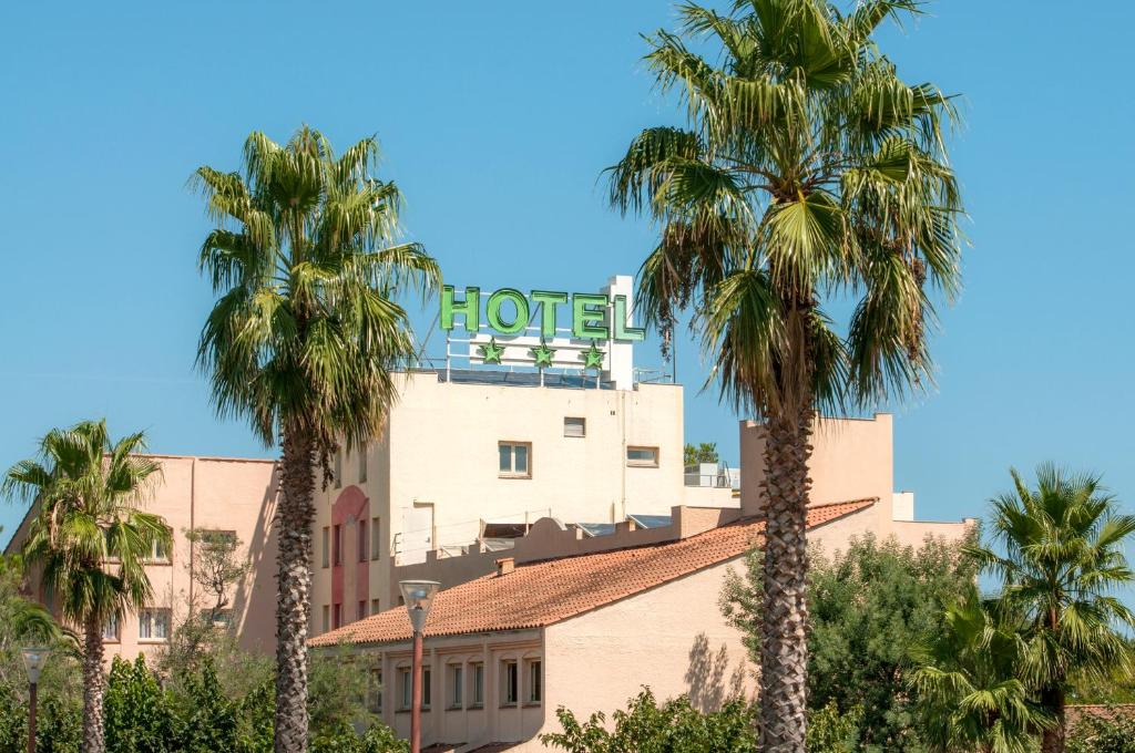 濱海阿熱萊斯的住宿－Hôtel Goélia Argelès Village Club，前面有棕榈树的酒店