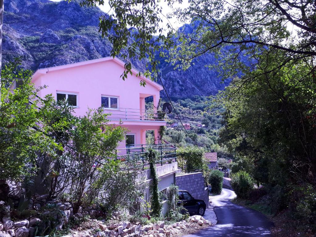 a pink house on a hill next to a road at EcoHouse Risan Studio in Risan