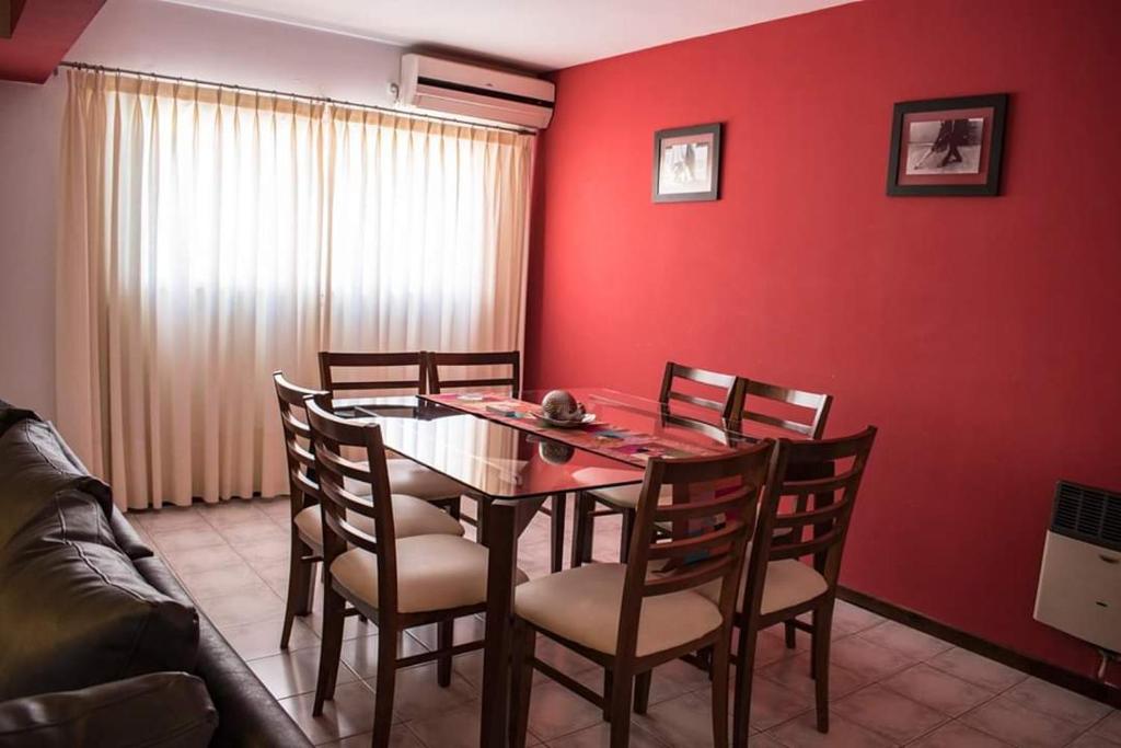 AMPLIO DEPARTAMENTO -EXCELENTE UBICACION- CON COCHERA في ميندوزا: غرفة طعام بجدران حمراء وطاولة وكراسي