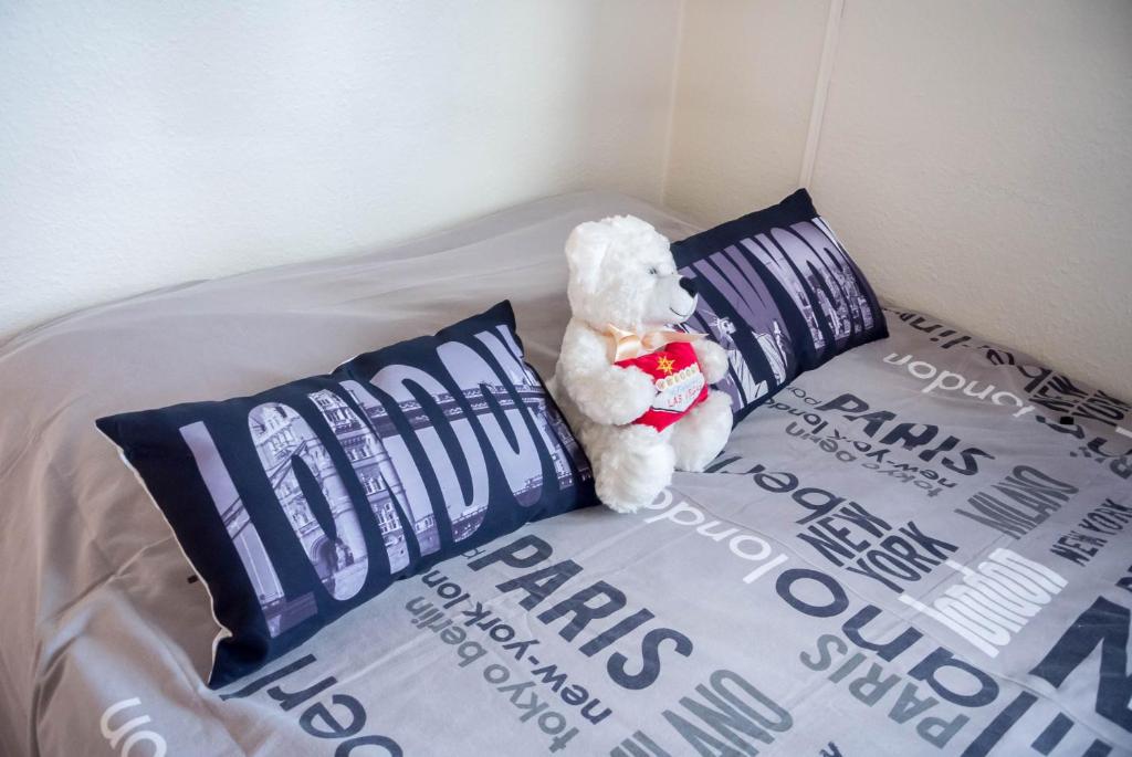 a teddy bear sitting on a bed with pillows at Travel Homes - The EastSide, Parking and downtown in Colmar