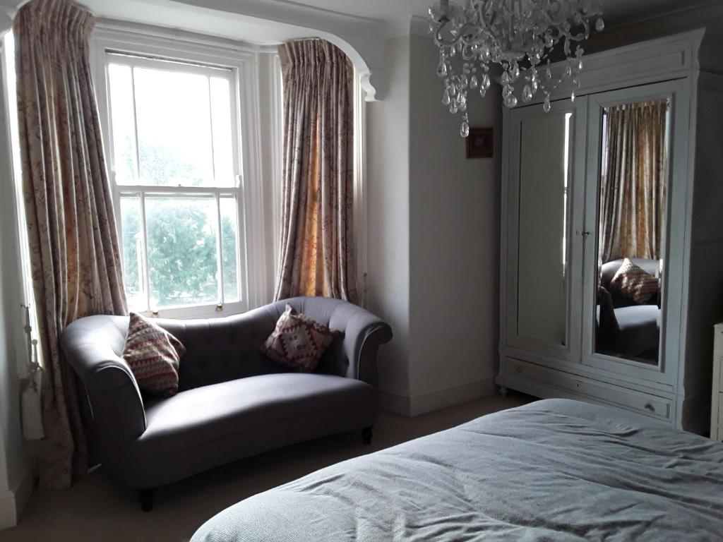a bedroom with a couch and a chair and a window at Town House Bridport Dorset in Bridport