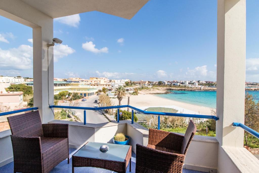 balcón con sillas y vistas a la playa en Hotel Il Faro Della Guitgia Tommasino, en Lampedusa