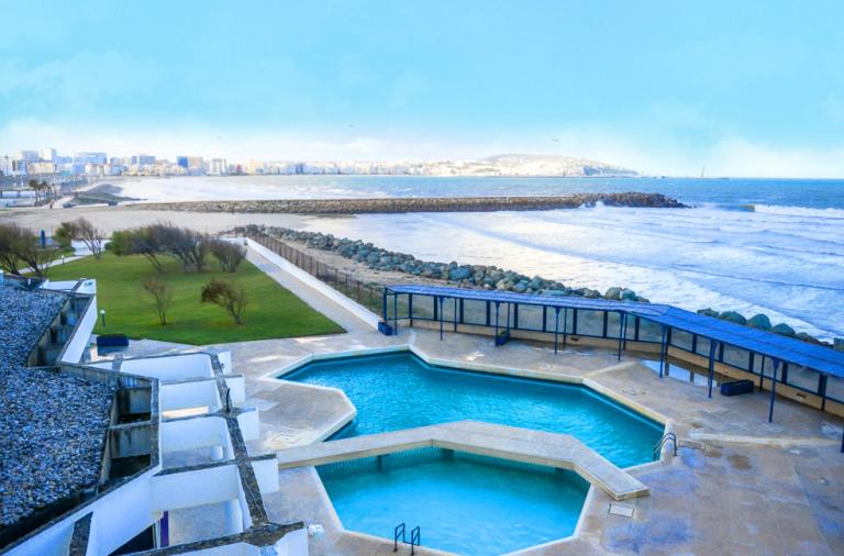una piscina junto a una playa junto al agua en UMH Tarik Hotel en Tánger