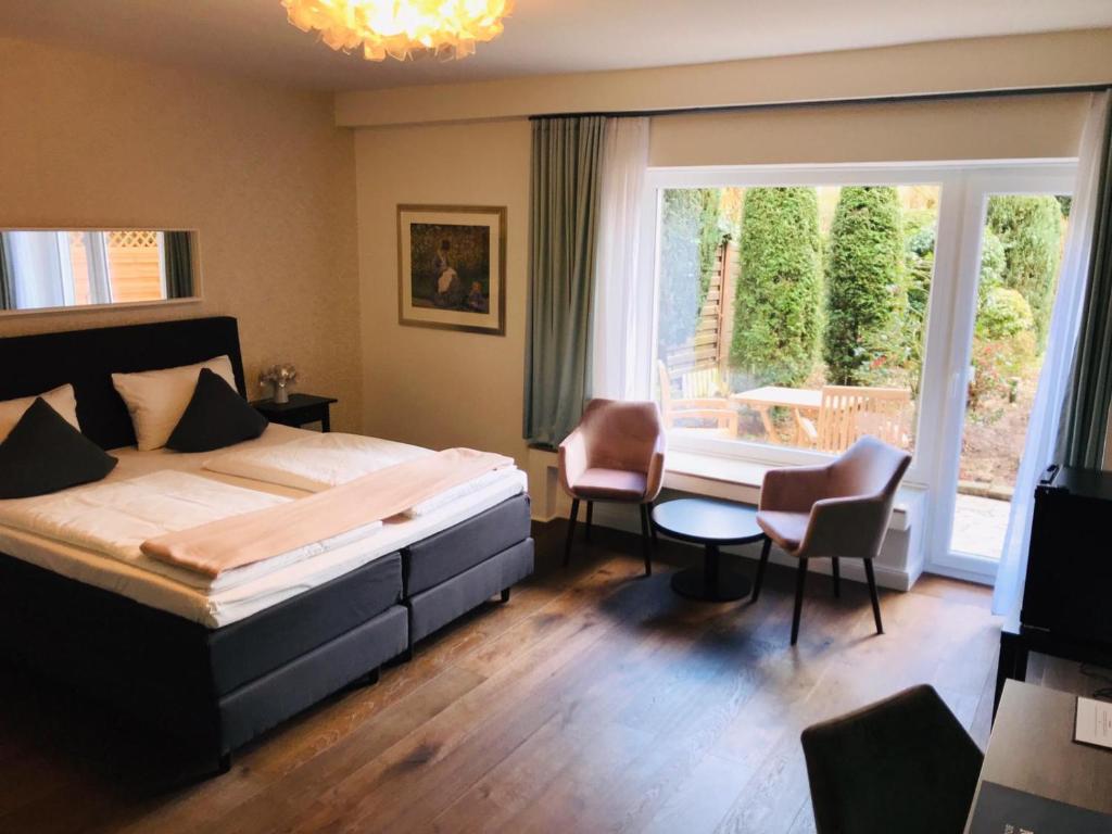 a bedroom with a bed and chairs and a window at Monopol Boutique Hotel in Bremen