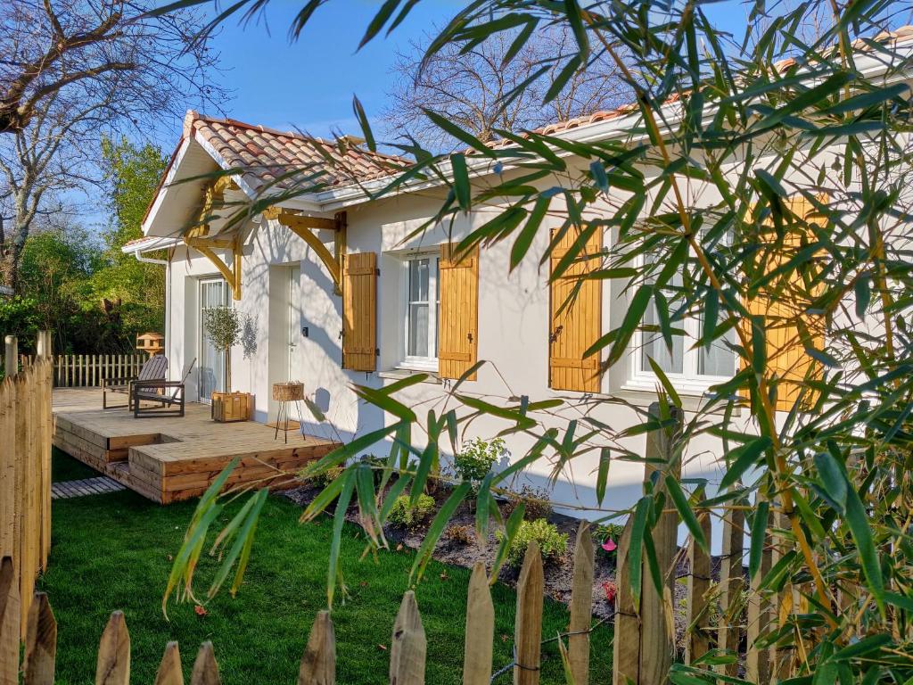 a small white house with a wooden deck at La Maison de Nini in Andernos-les-Bains