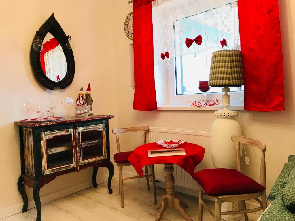 Poddębice的住宿－Mała Toscana，客房设有桌椅和带红色窗帘的窗户。
