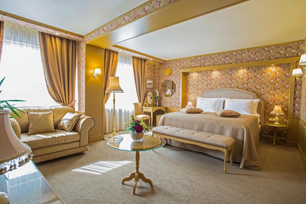 um quarto com uma cama, um sofá e uma mesa em Izmailovo Alfa Hotel em Moscou
