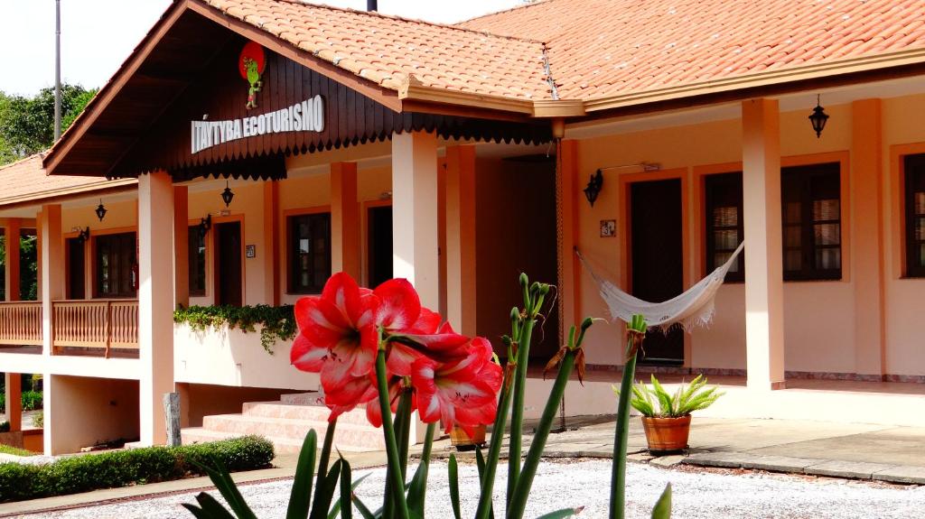 um edifício com uma flor vermelha à frente dele em Hotel Fazenda Itáytyba em Tibagi