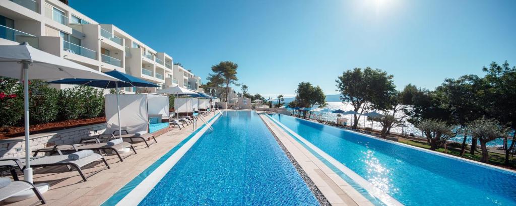 a swimming pool with chairs and umbrellas at a hotel at Girandella Valamar Collection Resort in Rabac