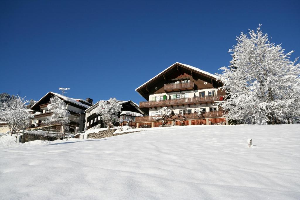 a ski lodge with snow on the ground in front of it at Hotel Adler Garni in Hirschegg