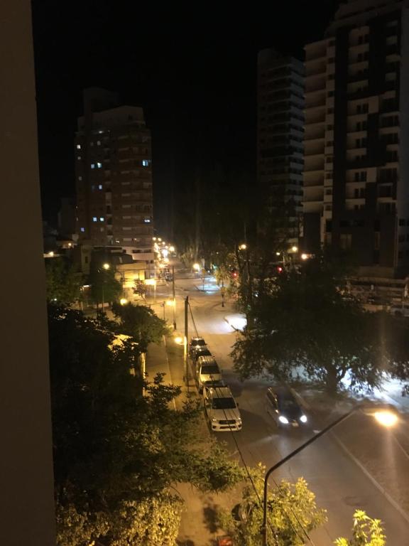 una calle de la ciudad por la noche con coches y luces de la calle en Apartamento Mig en Neuquén