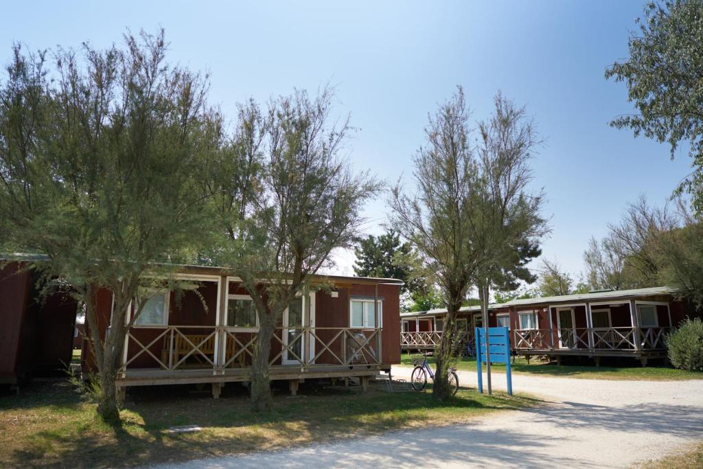 a row of cottages with trees in front at Camping Village Capalonga in Bibione