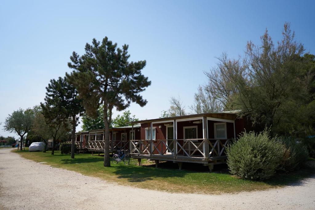 a cabin with a tree and a dirt road at Camping Village Capalonga in Bibione