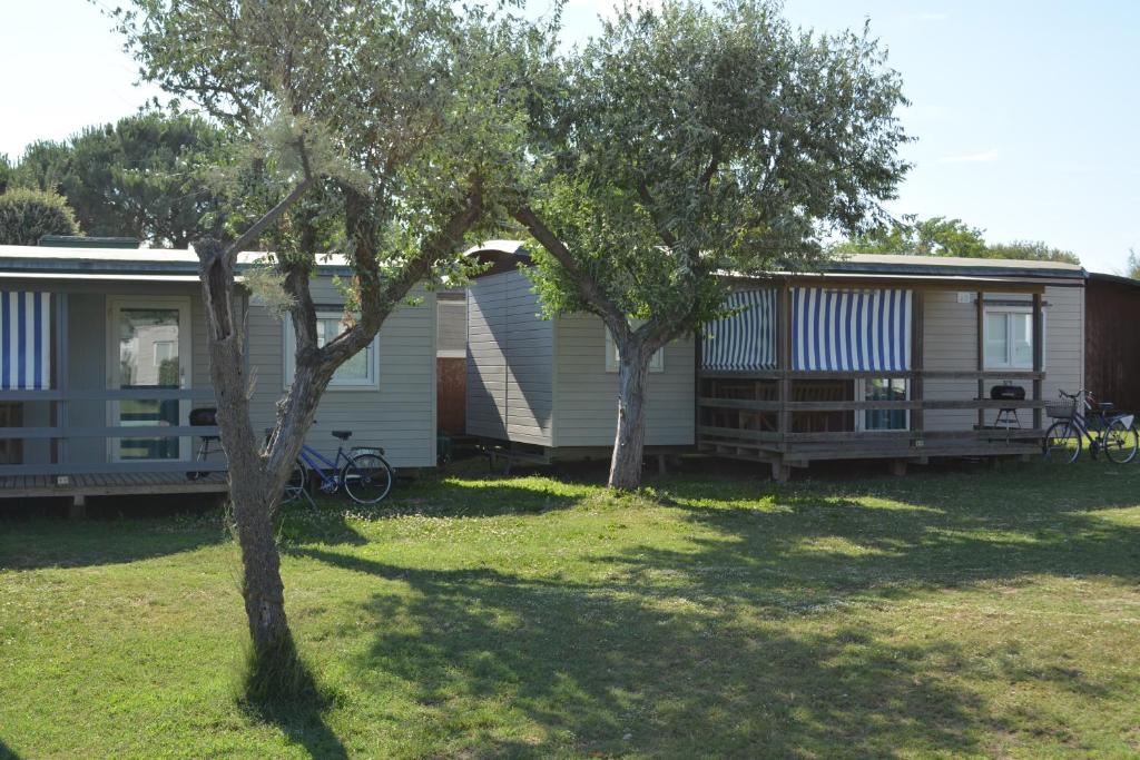 a couple of mobile homes in a yard with trees at Camping Village Capalonga in Bibione