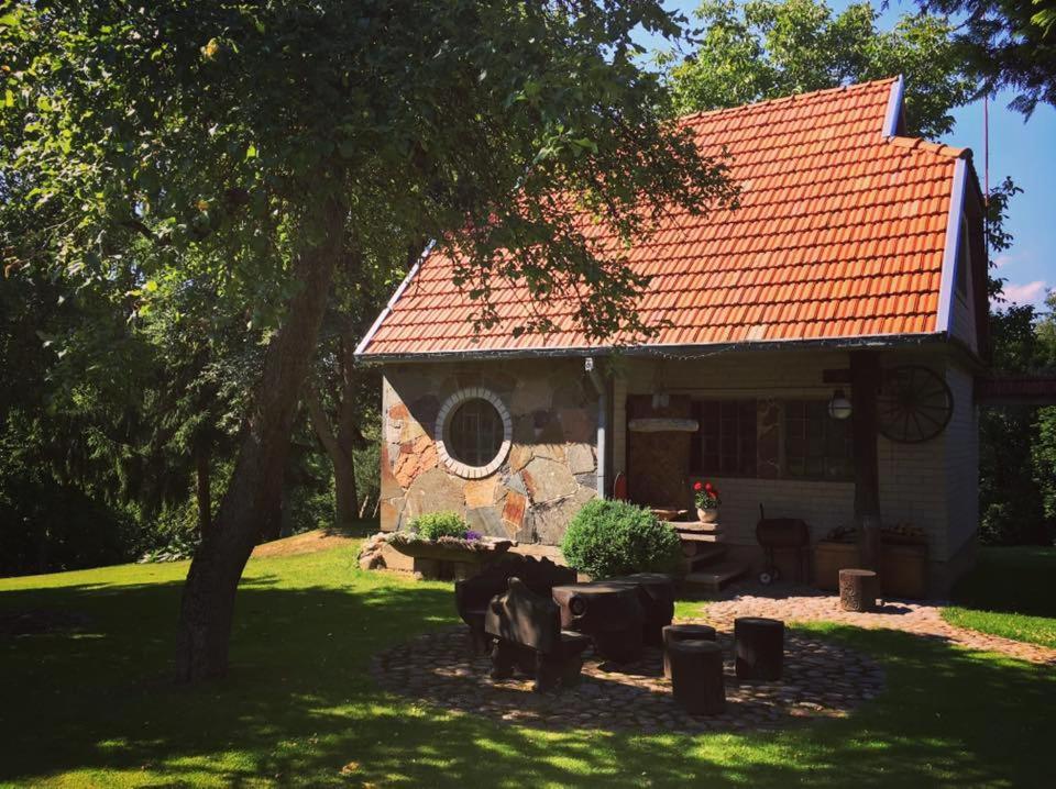 une maison avec un toit rouge et une table devant elle dans l'établissement Valuntynė, à Plokščiai