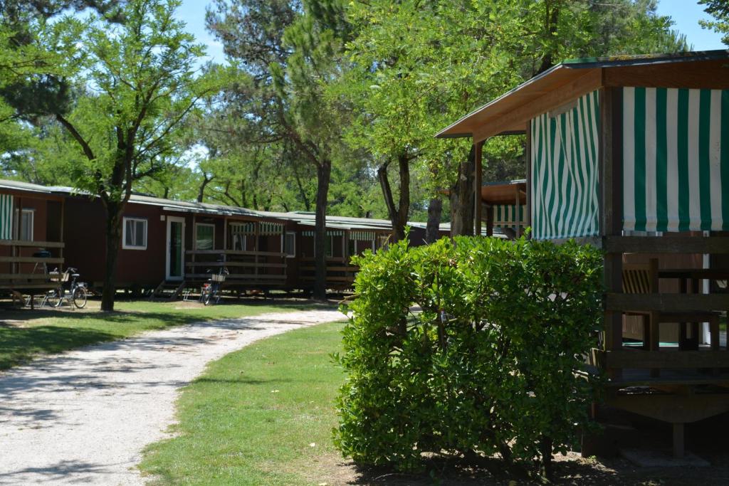 a group of cottages in a park with a bush at Camping Village Capalonga in Bibione