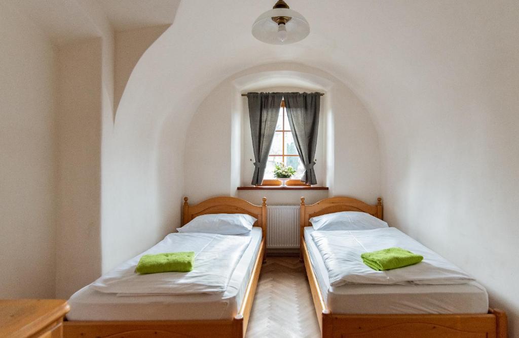 two beds in a small room with a window at Restaurace a penzion Stará pošta in Bečov nad Teplou