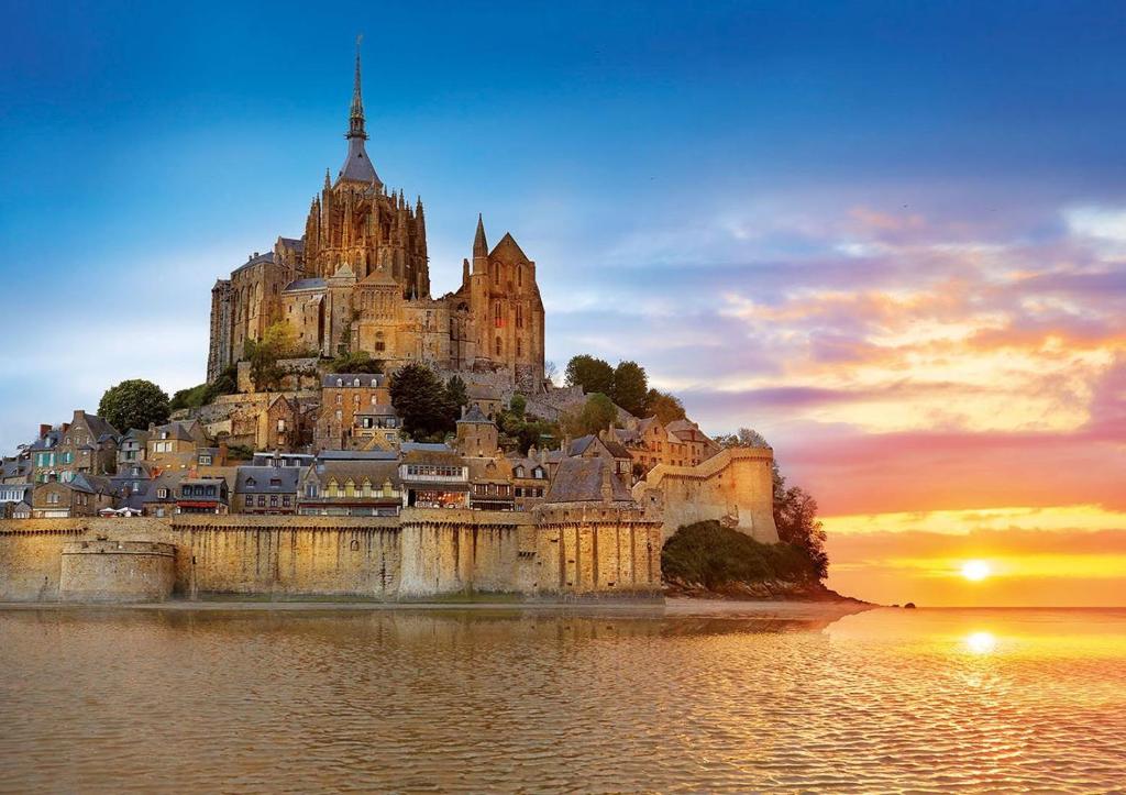 a castle on an island in the water at sunset at gite Tombelaine in Pontorson