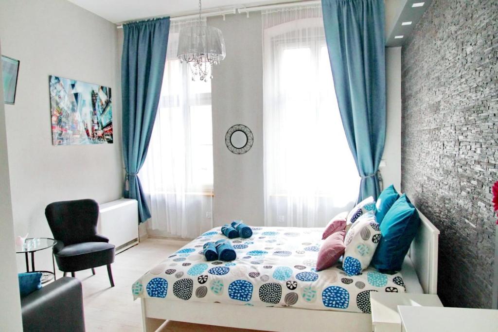 a bedroom with a bed with blue curtains and a chair at Grey Rooms in Wrocław