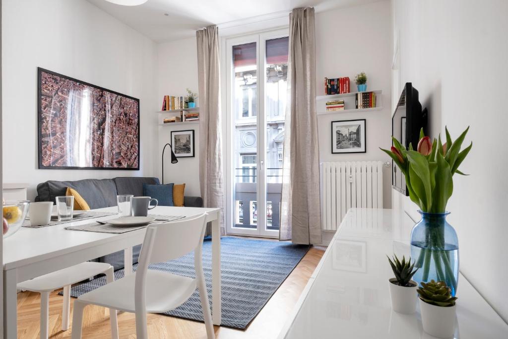 a white dining room and living room with a table and chairs at Appartamento dietro Fontana del Nettuno in Bologna