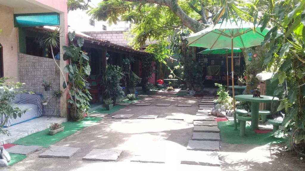 a patio with a table and a green umbrella at Suítes Brisa Mar in Cabo Frio