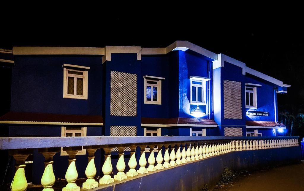 a blue building with white windows and a fence at Bijou Guest House in Baga