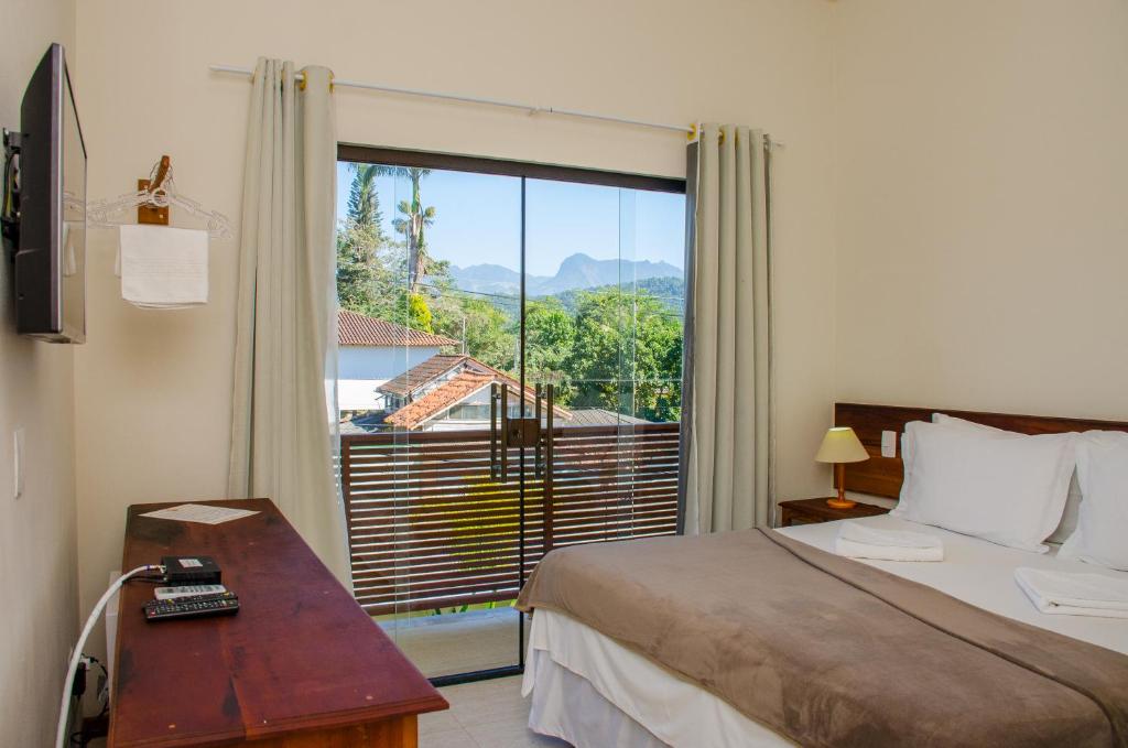 a hotel room with a bed and a large window at Pousada Maré Mansa in Paraty